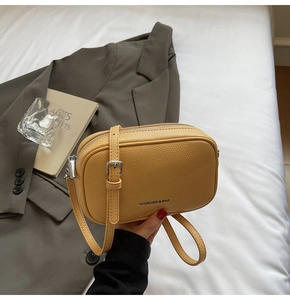 Détail d'un sac à bandoulière jaune en cuir grainé avec fermeture éclair argentée fine