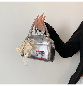 Détail du sac bowling argenté avec écusson chien cartoon et breloque en dentelle perlée