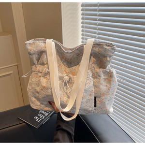 Detailed embroidery on light blue lace tote bag with floral patterns and woven handles