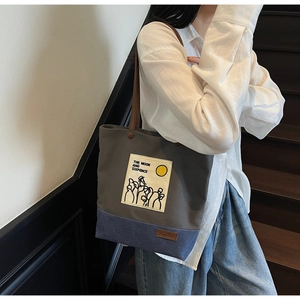 Detail of grey and navy canvas tote bag featuring graphic print and brown shoulder strap