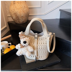 Détail du sac seau en cuir découpé au laser blanc crème avec son charmant petit ours