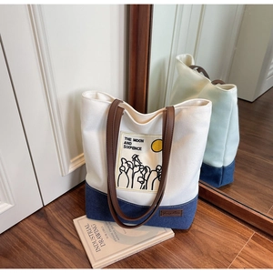 Detail of canvas tote bag with contrast denim base and literary illustration