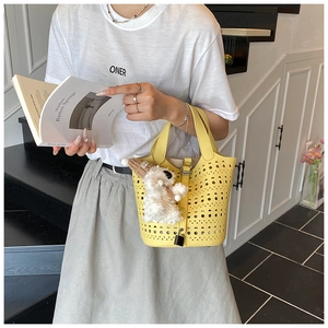 Détail du sac seau jaune en cuir ajouré avec un pendentif mignon en forme de chiot en peluche