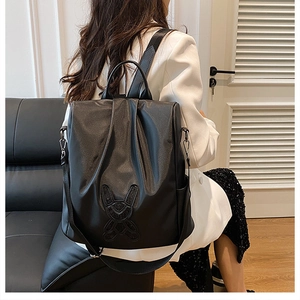 Detail of black synthetic leather backpack with cute rabbit linear decor and handle