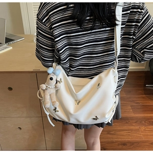 Détail du sac bandoulière blanc avec breloque papillon et pendentif peluche chien mignon