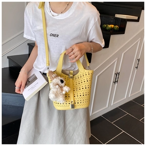 Détail du sac seau jaune ajouré avec serrure en métal et breloque chien en peluche