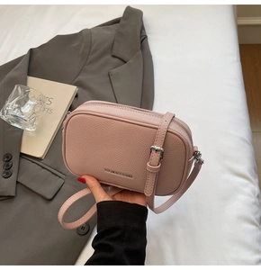 Détail du sac bandoulière rose en cuir grainé avec logo et boucles métalliques