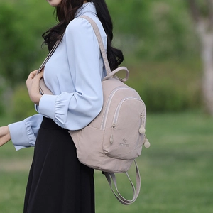 Outdoor view of a cream multifunctional backpack showing the shoulder strap and side profile