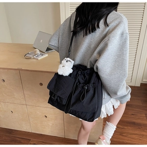 Detail of black nylon drawstring crossbody bag with multiple pockets and cute bear charm
