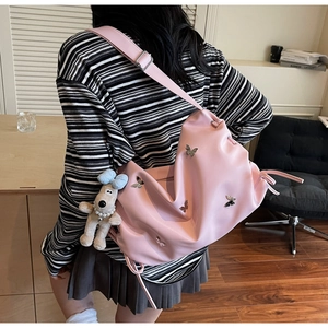 Détail d'un sac hobo rose en PU avec papillons 3D et charmant chiot en peluche