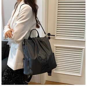 Detail showing a black nylon backpack with a sequin cartoon rabbit ear applique design