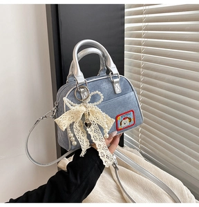Détail du sac bowling en denim bleu clair avec nœud en dentelle, perles et patch chien