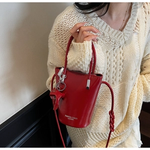 Detail of red glossy bucket bag featuring white text logo and a horse charm