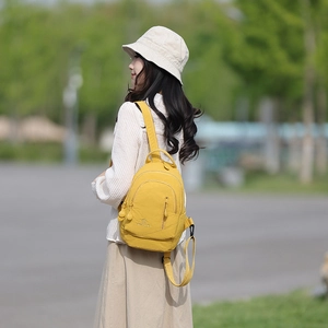 Detail of bright yellow canvas backpack with multi-layer zippers in a natural park setting