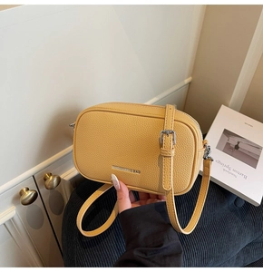 Détails du sac carré en cuir jaune avec texture de litchi et logo de marque en argent