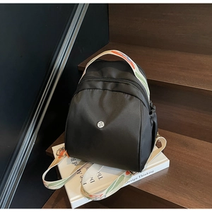 Dettaglio dello zaino in nylon nero con spallacci jacquard colorati su un libro di design