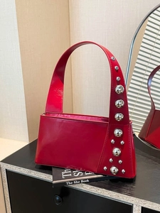 Red patent leather underarm bag with silver spherical rivets and wide shoulder strap