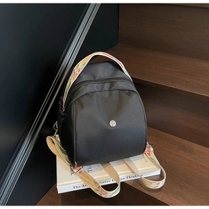 Dettaglio di un mini zaino in nylon nero con tracolla jacquard a motivi floreali