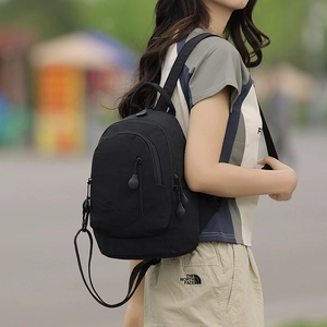 Outdoor lifestyle shot of a black nylon mini backpack with a stylish brand logo