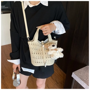 Détail du sac seau ajouré crème avec breloque ours en peluche et bandoulière