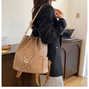 Detail of khaki fashion backpack showing rabbit sequin embroidery and side pocket