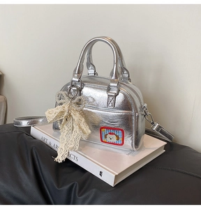 Détail du sac bowling argenté avec nœud en dentelle et écusson de chien mignon