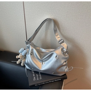 Détail d'un sac à main argenté métallisé avec papillons et charmant pendentif de chiot