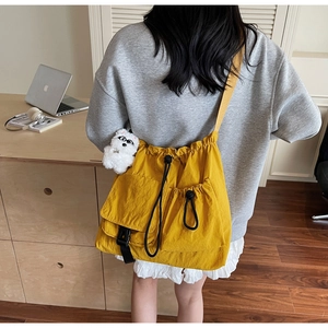 Detail of yellow drawstring crossbody bag with plush charm in a cozy workspace setting