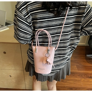 Close-up of pink bucket bag with leather texture and cute elephant charm on a model