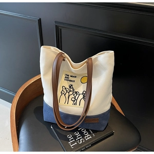 Close-up of contrast canvas tote bag with moon and sixpence print on a retro chair
