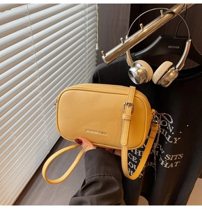 Vue détaillée du cuir litchi jaune et de la boucle argentée du sac à bandoulière