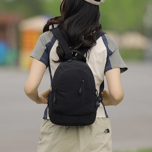 Close-up of black nylon backpack with front zipper pocket and MSSHUIA logo on back of model