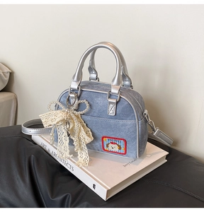 Détail du sac bowling en denim bleu avec écusson de chien et nœud en perles et dentelle