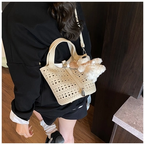Détail du sac seau crème avec motif ajouré au laser et charmant ours en peluche
