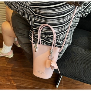 Top-down view of pink bucket bag with elephant pendant on model in indoor setting