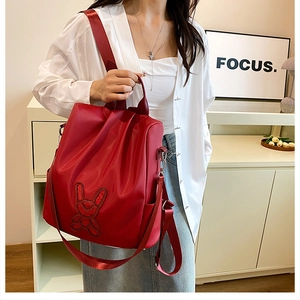 Detail of red water-resistant backpack featuring a sequined rabbit patch on glossy fabric