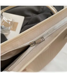 Close-up of smooth silver metal zipper on minimalist beige leather tote bag detail