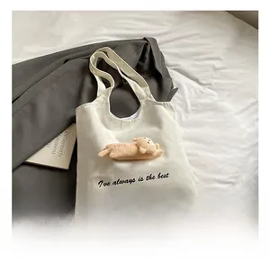Detail of canvas tote bag featuring a cute plush bear doll and shoulder straps