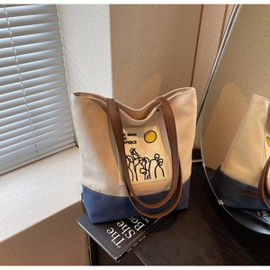 Detail of canvas tote bag showing contrast denim stitching and the Moon and Sixpence patch