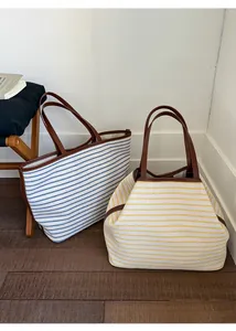 Detail view of striped canvas tote bags with leather handles and adjustable structure