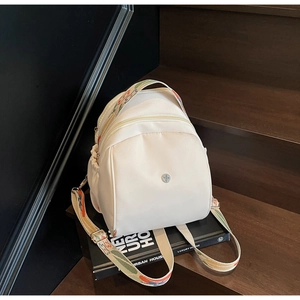 Dettaglio di uno zaino in nylon bianco panna con spallacci larghi ricamati colorati