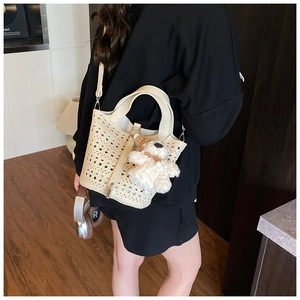 Détail du sac seau beige ajouré avec motifs découpés au laser et pendentif peluche