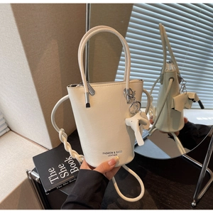Detail of off-white leather bucket bag with an elephant charm and top handle strap