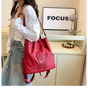 Detail of red water-resistant backpack featuring a sequined bunny design and side pocket