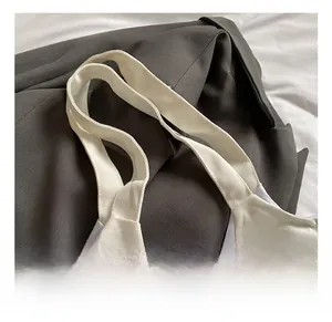 Detail shot of the wide cotton woven handle on a white canvas tote bag for durability