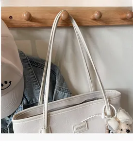 Detail of herringbone texture tote bag with a cute bear charm on a wooden rack