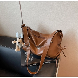 Détail du sac hobo en similicuir marron avec boucle papillon et breloque chiot