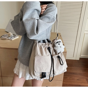 Detailed view of beige nylon crossbody bucket bag with drawstring and pockets