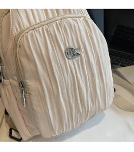 Close-up of pleated beige nylon fabric and metallic logo on casual sport backpack