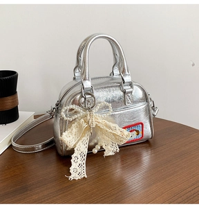 Détail d'un sac bowling argenté avec nœud en dentelle et perles et écusson de chien mignon
